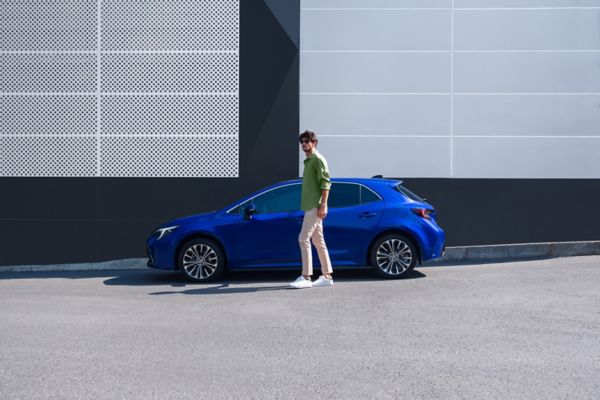 mavi Corolla Hatchback Hybrid araç yanında duran bir adam