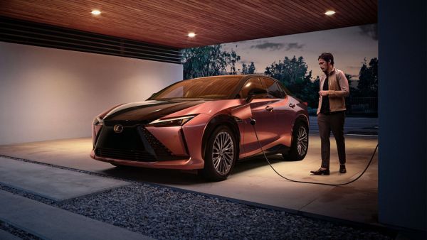 a man plugging a Lexus RZ 450e into a home charging station