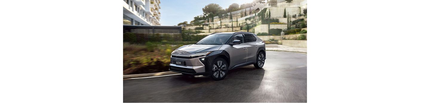 Ein silber-schwarzer SUV fährt auf einer kurvigen Straße in einer modernen Wohngegend bei Tageslicht.