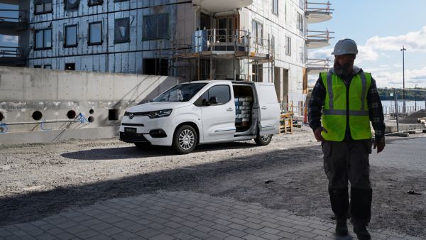 a person wearing a high vis walking in front of a Toyota vehicle