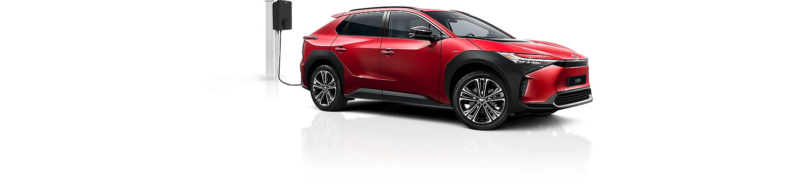 Ein roter Toyota C-HR Plug-in, der über eine Ladesäule geladen wird.