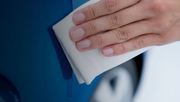 кадър на ръка, почистваща син автомобил с бяла кърпа