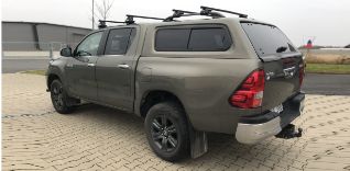 Hnědý pick-up Toyota Hilux s nástavbou a střešním nosičem.