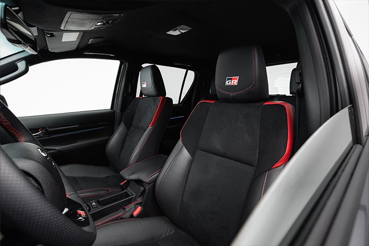 Sportowe fotele kierowcy i pasażera w Toyocie Hilux z logo GR SPORT.