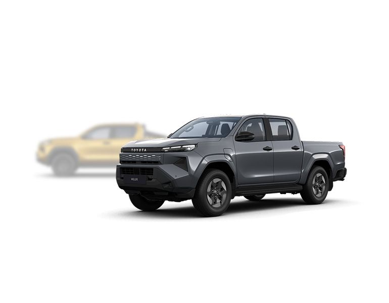 Grauer Hilux BEV steht diagonal zur Kamera, im Hintergrund ist unscharf ein gelber Hilux Mild-Hybrid zu erkennen