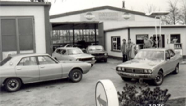 Ein Schwarzweiß-Bild von einem Innenhof mit mehreren alten Toyota-Fahrzeugen