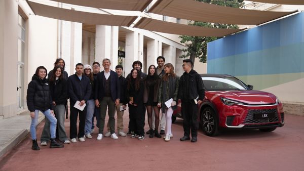 A group of people surrounding a Lexus