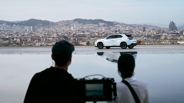 A man and woman in the forefront of a Lexus UX