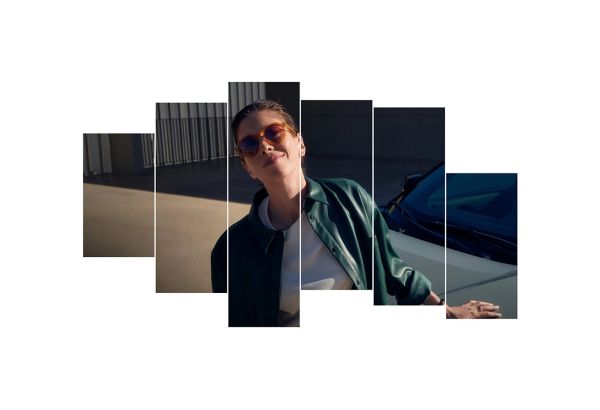 Eine Frau mit Sonnenbrille lehnt sich lächelnd an eine Motorhaube.