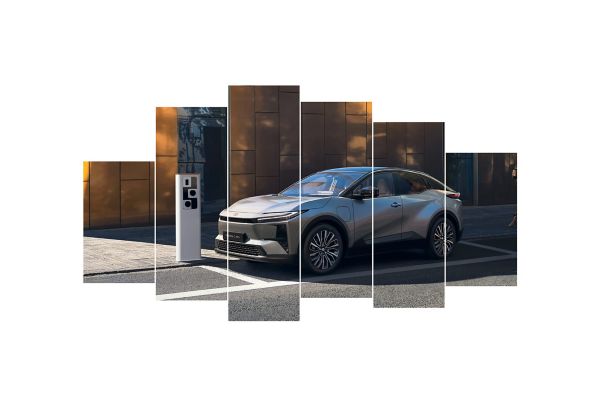Ein silberner Toyota C-HR steht an einem Straßenrand neben einer Ladesäule.