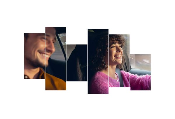 Zwei lächelnde Personen in einem Auto, ein Mann in einem braunen Hemd und eine Frau in einem rosa Pullover, genießen gemeinsam eine Autofahrt.
