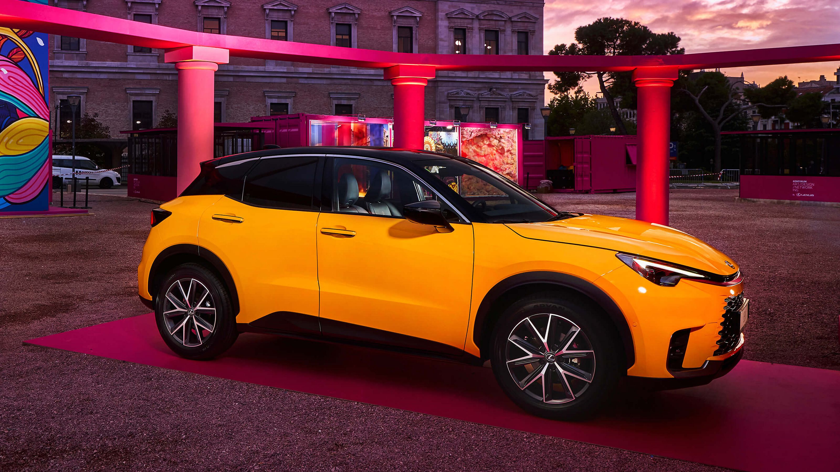 Ein gelber Lexus LBX vor einer kunstvollen Kulisse aus Säulen
