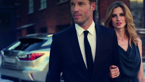 A man in a suit walking away from a Lexus
