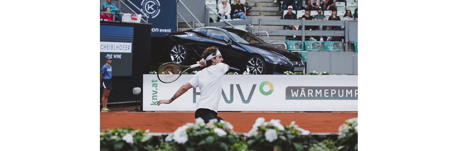 Roger Federer on a tennis court with a Lexus in the background