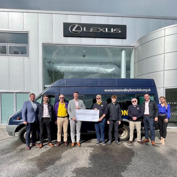 people holding a cheque in front of Lexus