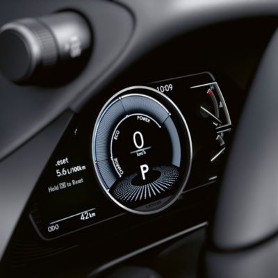 Digitales Display am Armaturenbrett eine Lexus mit Anzeige der Geschwindigkeit (0 km/h), Leistungsanzeige und Kraftstoffverbrauch (5,6 L/100km) bei einem Kilometerstand von 42 km.