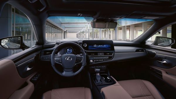 Die Innenansicht eines Lexus ES zeigt das Armaturenbrett mit Digitalanzeige, Lenkrad und Hightech-Bedienelementen vor einem modernen architektonischen Hintergrund.