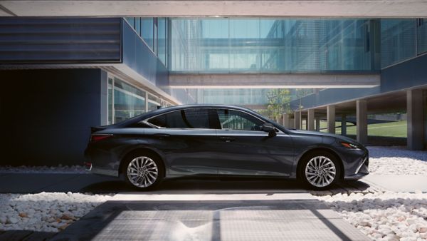 Ein schwarzer Lexus ES steht geparkt im Innenhof eines Gebäudes mit modernen Glaselementen