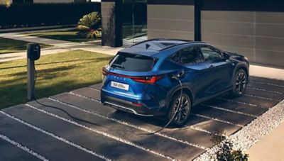 Blauer Lexus NX lädt an einer privaten Ladestation vor einem Haus.
