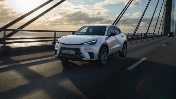 Ein silberner Lexus LBX Relax fährt über eine Brücke.