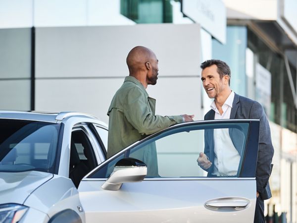 Zwei Personen unterhalten sich neben einem Lexus