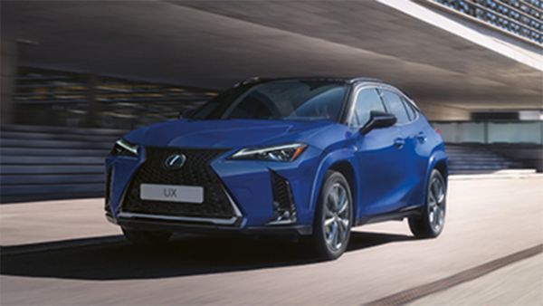 Ein blauer Lexus UX fährt vor einem modernen Gebäude vorbei