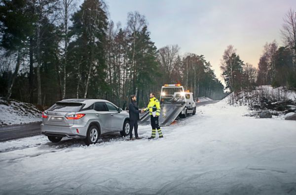 Ein Pannenhelfer mit einem Lexus und dessen Fahrer in verschneiter Landschaft