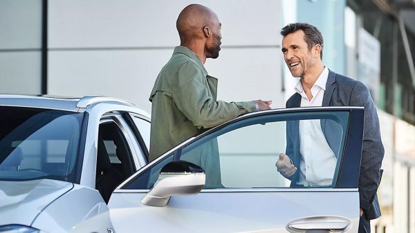 Zwei Männer unterhalten sich neben einem Lexus vor der geöffneten Fahrertür