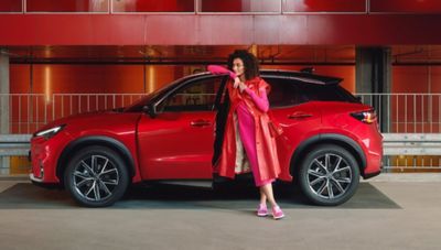 Roter Lexus in Parkhaus, Frau lehnt an offener Fahrertür.