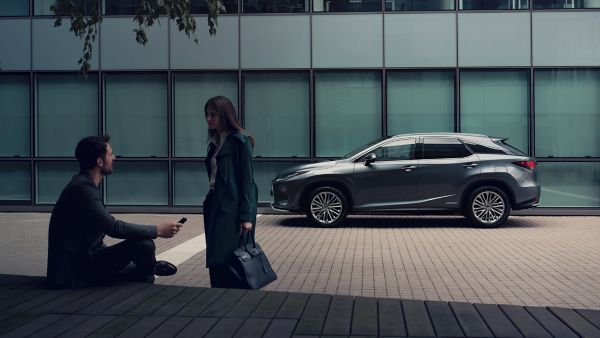 two people talking next to a Lexus car