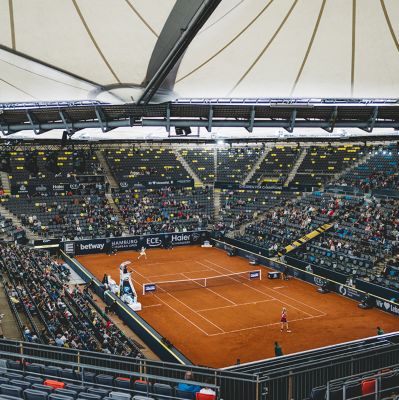 Ein Tennisplatz in einer großen Arena mit vielen Zuschauern 