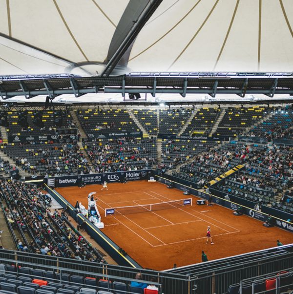 Ein Tennisplatz in einer großen Arena mit vielen Zuschauern 