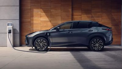 Grauer Lexus lädt an einer Wallbox vor moderner Holzfassade.