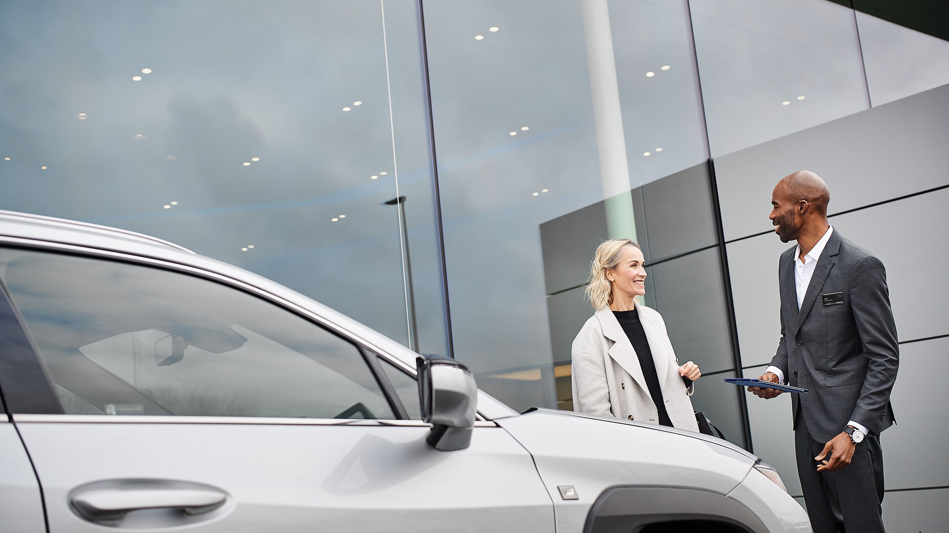 Zwei Menschen unterhalten sich vor einem Lexus Autohaus