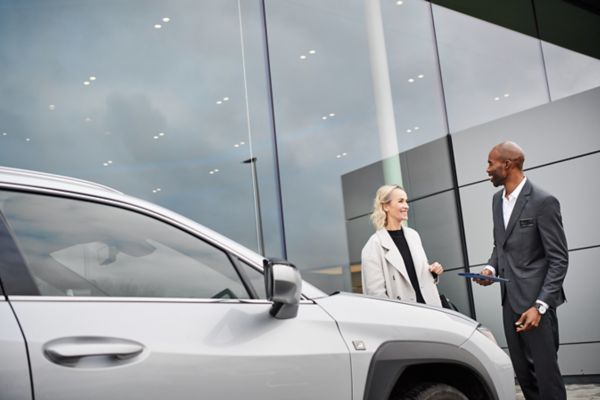 Zwei Menschen unterhalten sich vor einem Lexus Autohaus