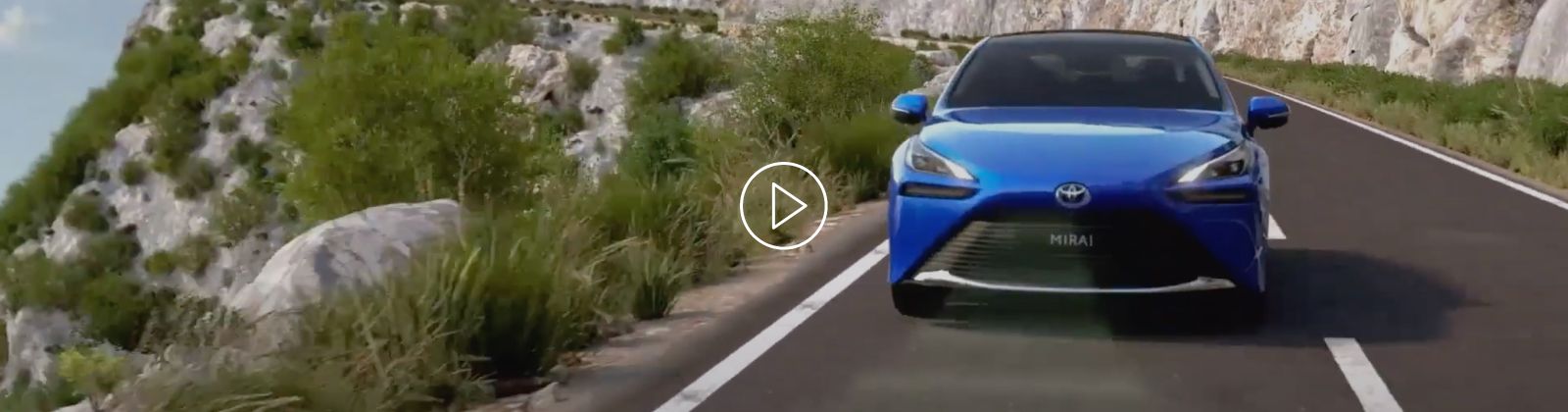 Kadr z filmu: Toyota Mirai jedzie drogą wśród górskiego krajobrazu.