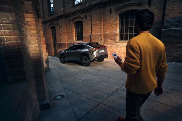 man walking towards a Toyota bZ4X on his phone