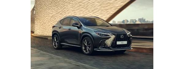 Ein dunkelgrauer Lexus NX fährt an einer Stadtkulisse vorbei