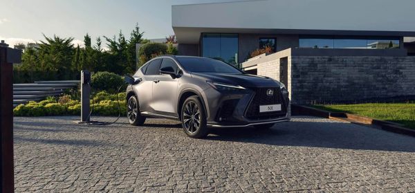 A Lexus NX plugged into a charger outside a home