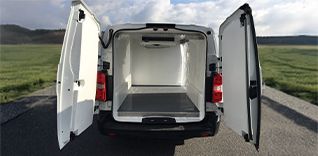 Žena pomáhá muži na invalidním vozíku nastoupit do automobilu.