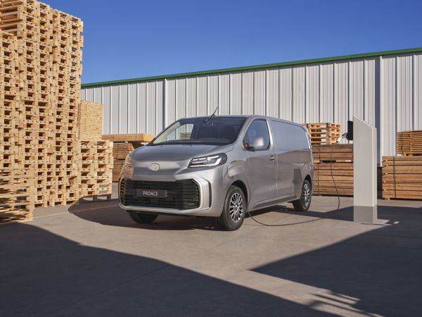 Grauer Toyota Proace Electric an Ladestation und im Hintergrund ist ein graues Gebäude zu sehen.