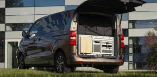 Hnědé rodinné MPV s otevřenými zadními dveřmi a vestavěnou kuchyňkou.