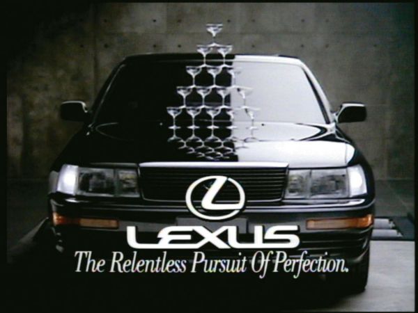 Eine Champagner-Glas Pyramide auf der Motorhaube eines Lexus LS, darunter der Schriftzug The relentless Pursuit of Perfection