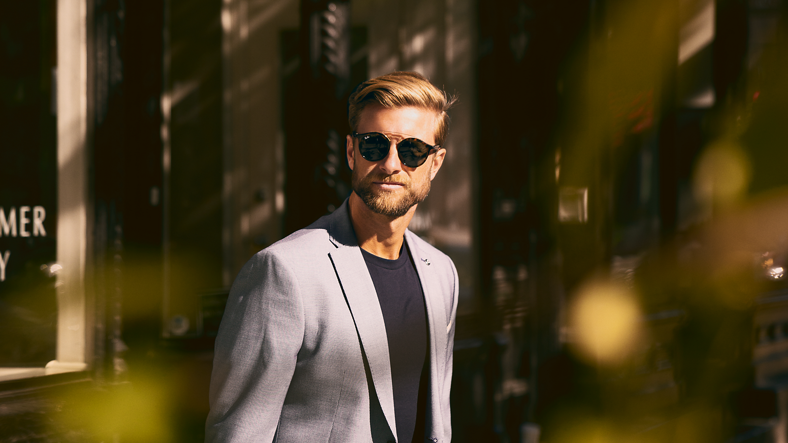 Mann mit Sonnenbrille und Anzug schaut lässig zur Seite.