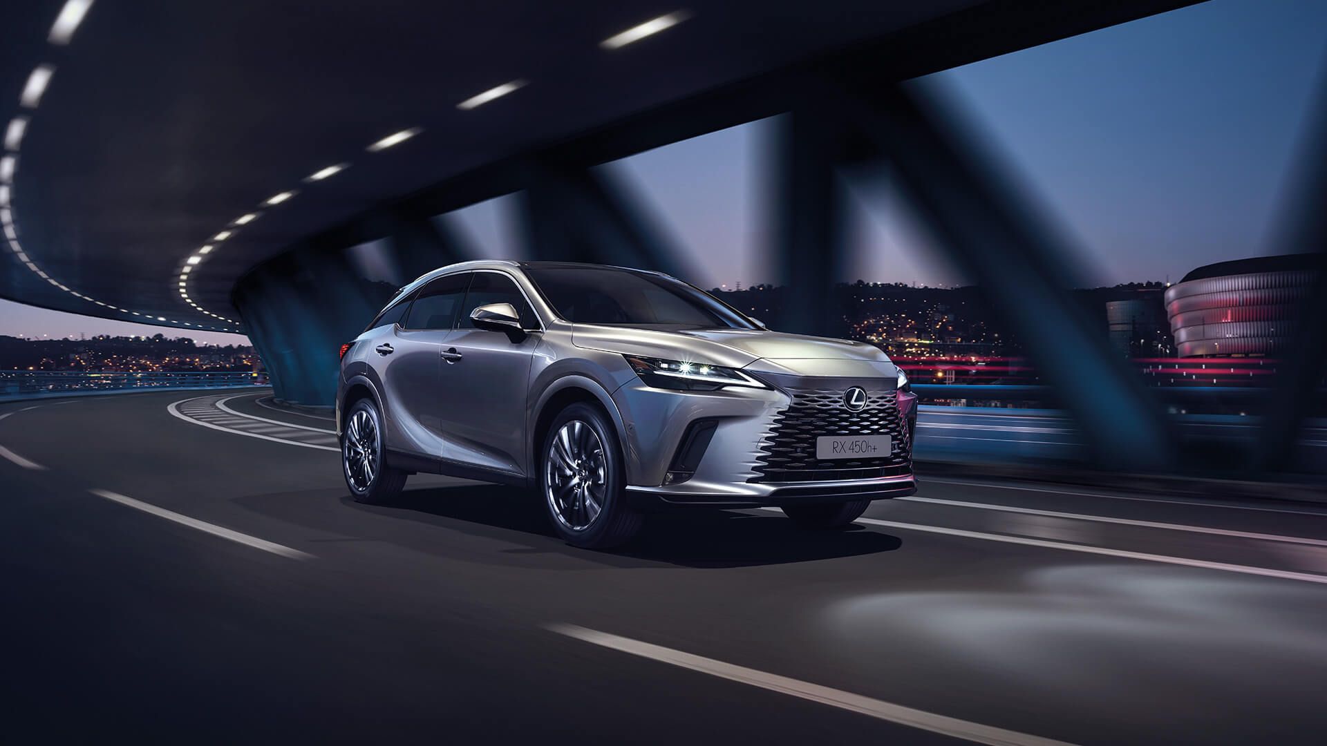 Ein eleganter silberner Lexus RX fährt in der Abenddämmerung über eine modern beleuchtete Autobahn