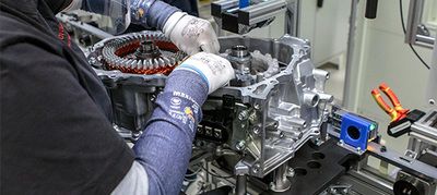 Ręce serwisanta pracującego przy rozłożonym silniku.