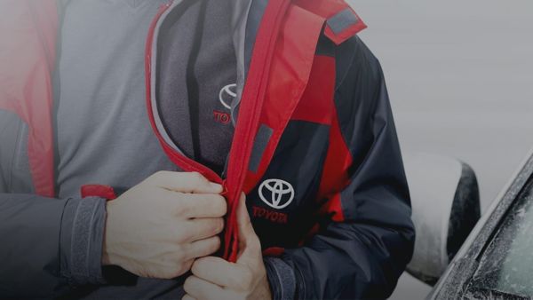 Close up of a man zipping up a Toyota coat