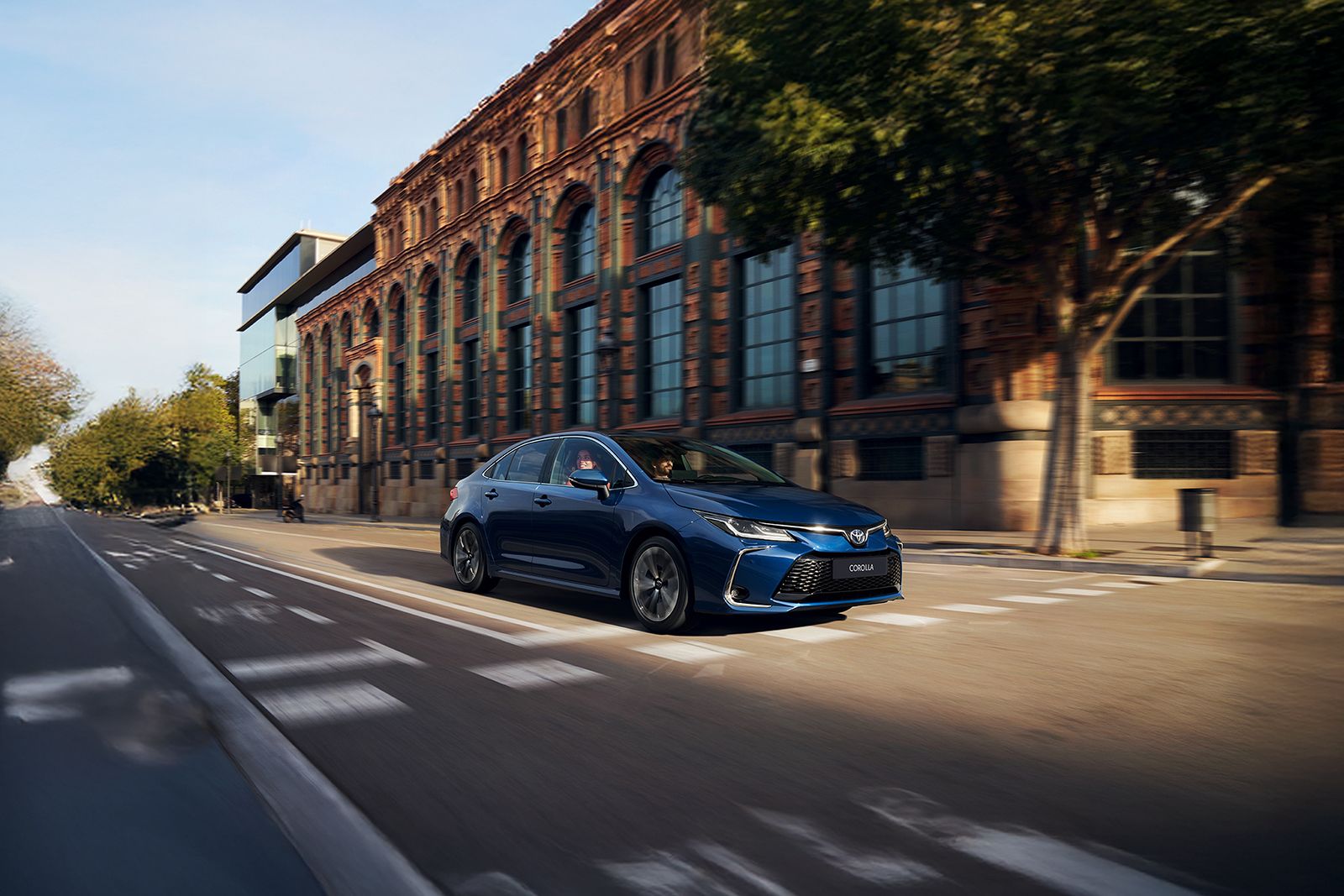 A Toyota Corolla Sedan drives in the city on a bright day