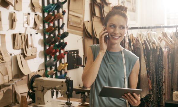 Woman on phone holding tablet in textiles shop