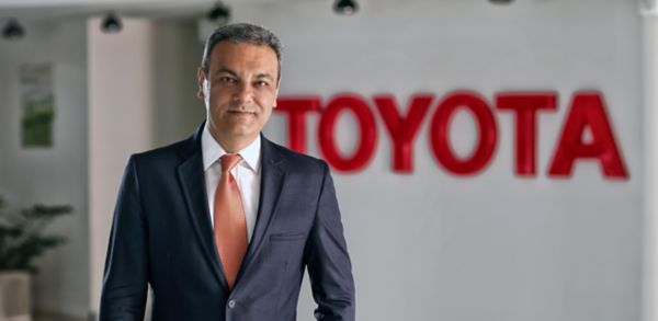 Arkada Toyota logosu ve önünde Toyota'nın CEO'su